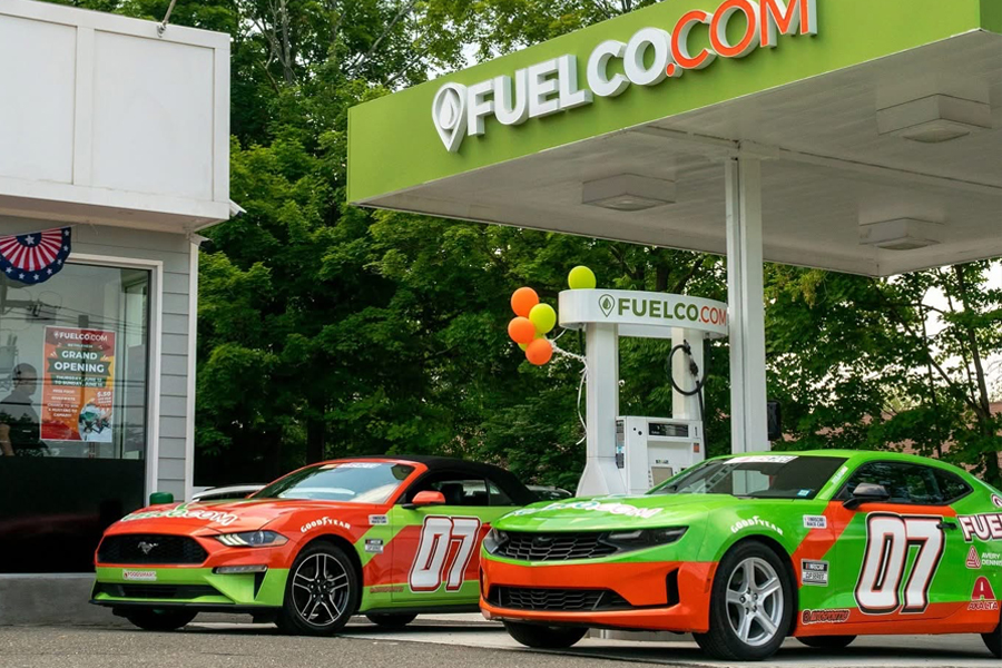 Green convertible Camaro in front of a garage and Fuelco.com gas station